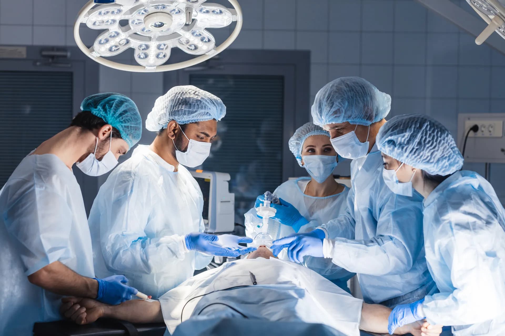 OP-Team mit Anästhesietechnischen Assistenten unter OP-Lampe